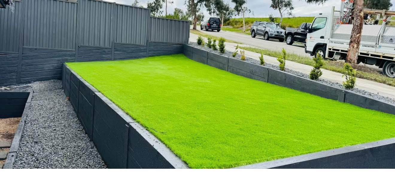 Raised lawn finished with dark retaining walls, our truck on the street