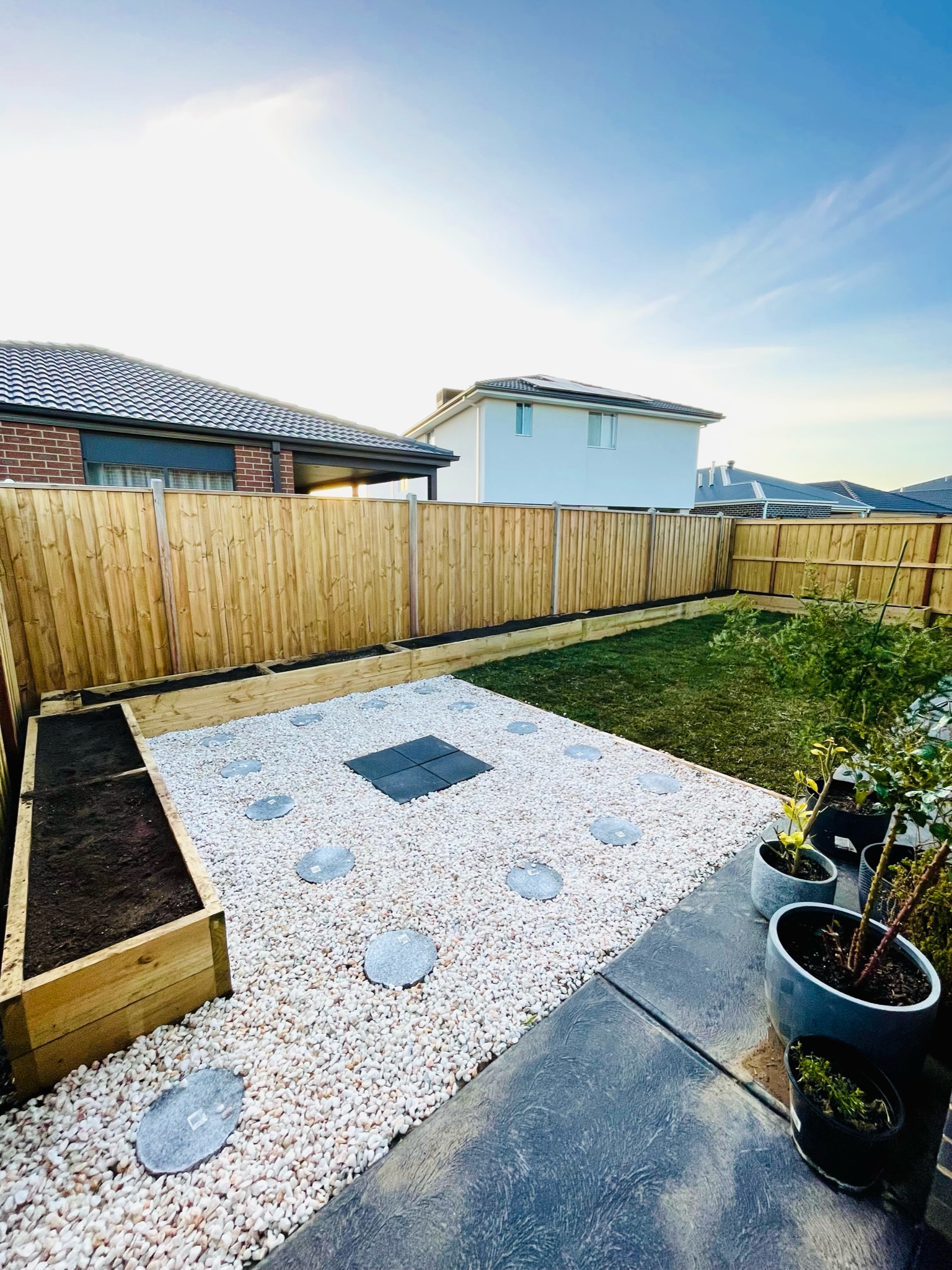 Backyard with raised timber garden beds and a pebble courtyard