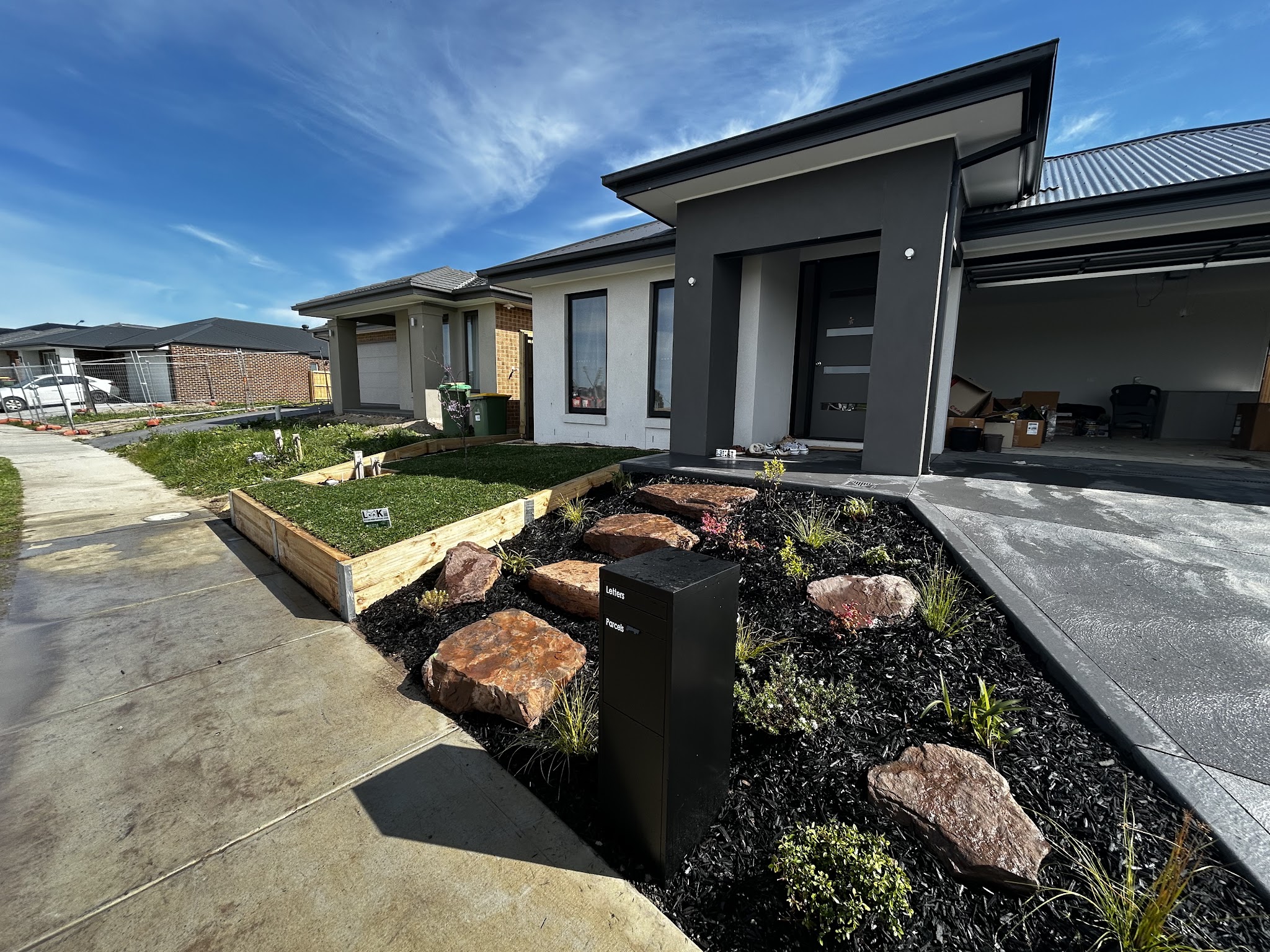 Finished front yard with feature boulders, stepping pavers and black mulch