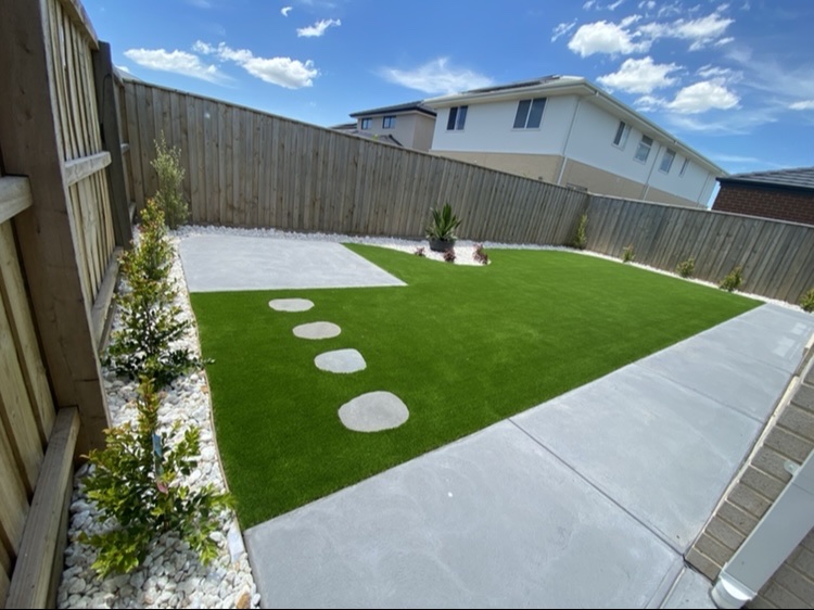 Backyard lawn with round stepping stones and a concrete edge